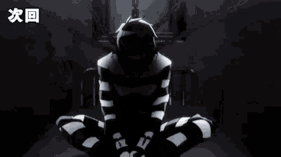 a man in a prison uniform is sitting on the floor in a cell with chains around his legs .