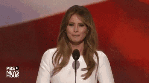 a woman in a white dress is standing in front of a microphone on a stage .