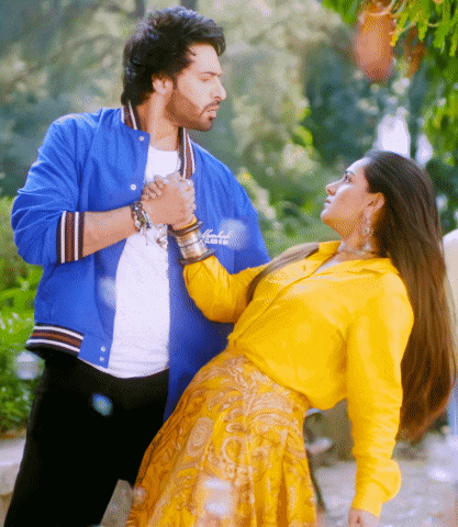 a man in a blue jacket holds the hand of a woman in a yellow dress