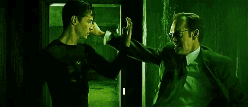 two men in suits and glasses are standing next to each other in a dark room .