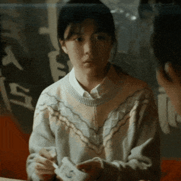 a woman in a sweater is holding a card with the letter s on it