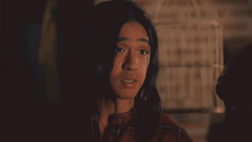 a woman with long hair is standing in a dark room looking at the camera .