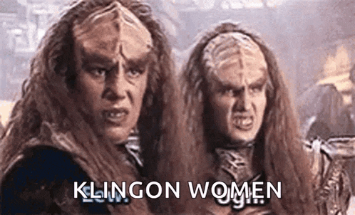 a couple of aliens with long hair are standing next to each other with the words `` klingon women '' written above them .