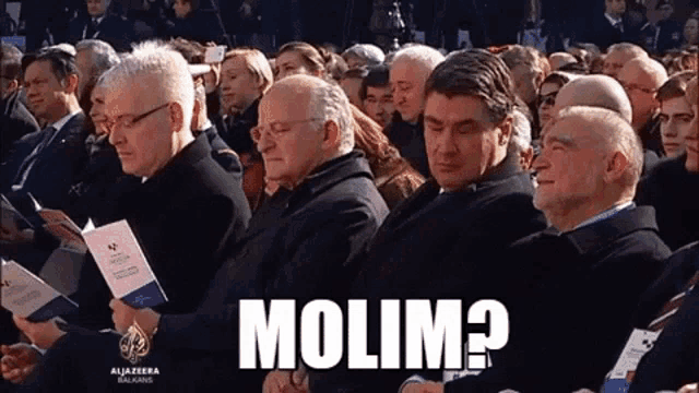 a group of people sitting in front of a sign that says molim on it