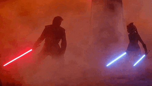 a man and a woman are standing next to each other holding lightsabers .