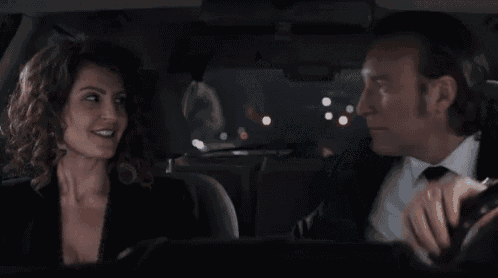 a man and a woman are kissing in a car at night .