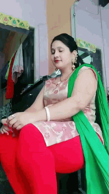 a woman in a pink and green dress is sitting in a chair