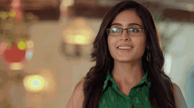 a woman wearing glasses and a green top smiles