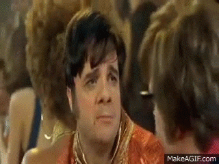 a man is making a funny face while sitting in a crowd of people at a party .