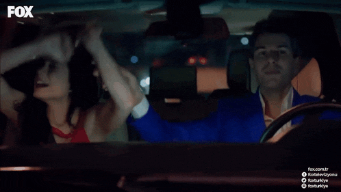 a man in a blue suit is driving a car with a woman holding his hand