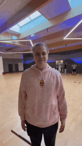 a man wearing a pink hoodie with spongebob on it is standing in a gym .