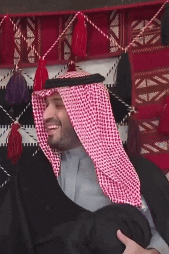 a man wearing a keffiyeh and a robe smiles