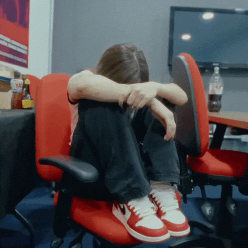 a woman is sitting in a red chair with her head down
