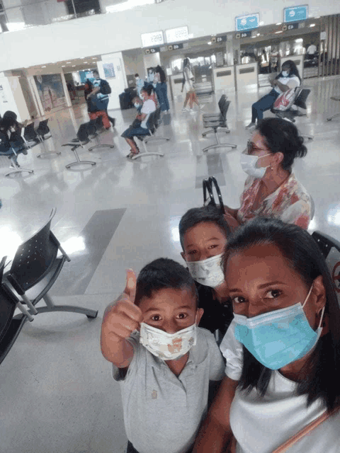 a woman and two children wearing masks at an airport