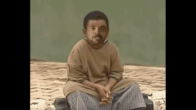 a young boy is sitting on a bench with a cigarette in his mouth and looking at the camera .