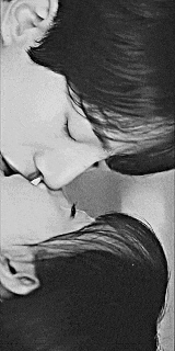 a black and white photo of a man and woman kissing each other .