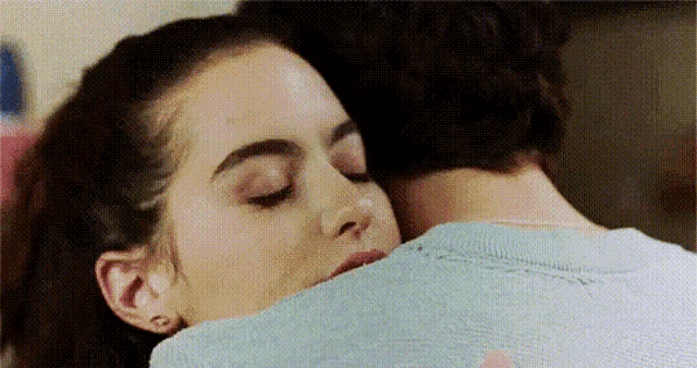 a woman is kissing a man on the neck while they are hugging each other .
