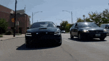 a dodge charger is driving down a street next to another car