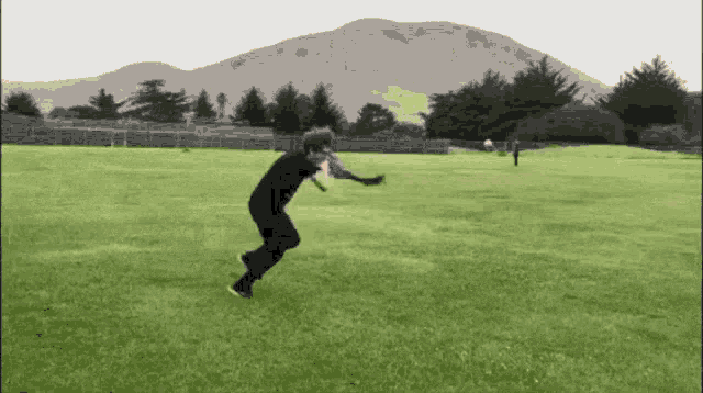 a man in a black shirt is running in a field