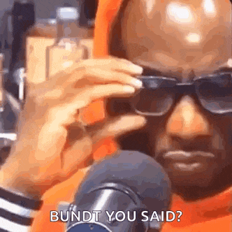 a man wearing sunglasses is talking into a microphone while holding his hand to his face .
