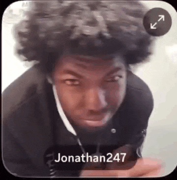 a man with curly hair is making a funny face while wearing headphones .