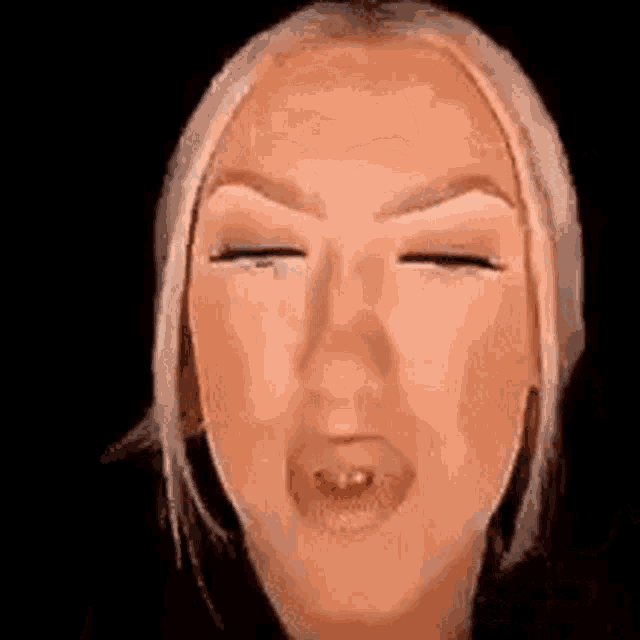 a close up of a woman making a face with her eyes closed .