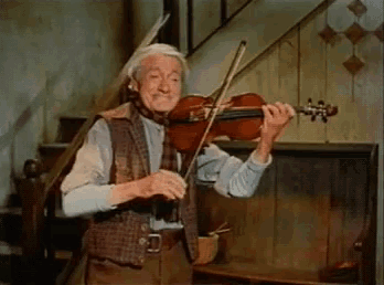a man is playing a violin in a room with stairs in the background