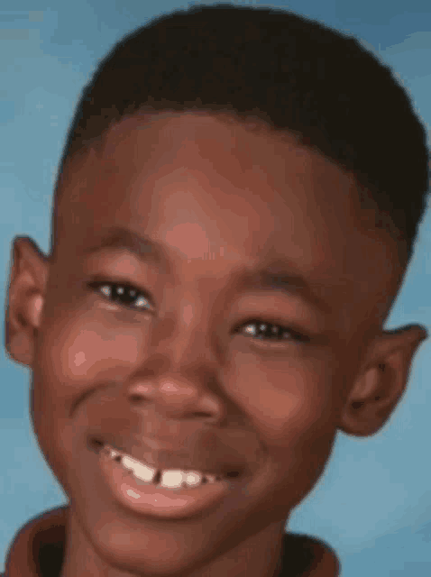 a young boy with a very short haircut is smiling
