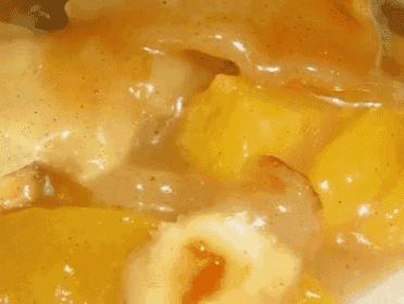 a close up of a yellow sauce with a few pieces of food in it