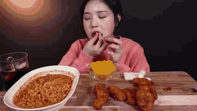 a woman is sitting at a table eating a bowl of rice and chicken