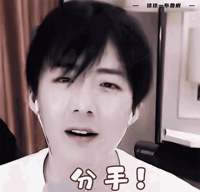 a young man wearing ear buds looks at the camera with a yamaha piano in the background