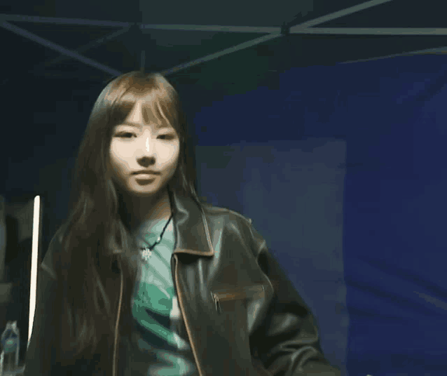 a young woman wearing a leather jacket and a green shirt