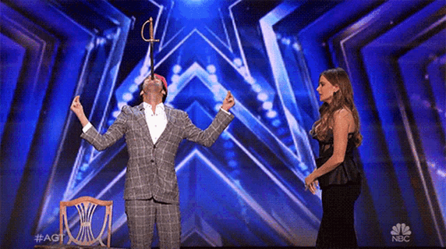 a woman stands next to a man on a stage with a nbc logo on it