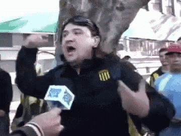 a man is talking into a microphone while holding his fist up in the air .