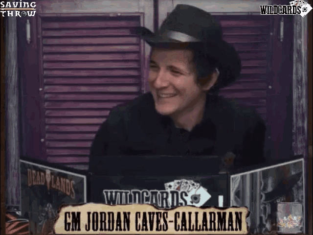 a man wearing a cowboy hat is sitting in front of a sign that says wildcards