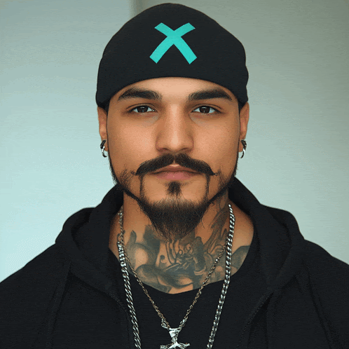 a man with a beard wears a black beanie with an x on it