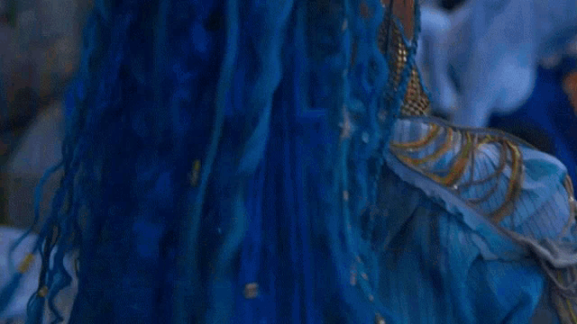 a close up of a woman wearing a blue dress and blue eye shadow