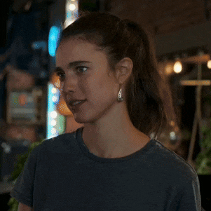 a woman wearing a ponytail and earrings looks serious