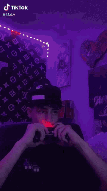 a young man is playing a video game in a room with purple lights and a louis vuitton wallpaper