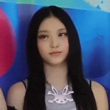 a woman with long black hair wearing a necklace with a bunny pendant