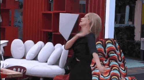 a woman in a black dress is sitting on a colorful couch