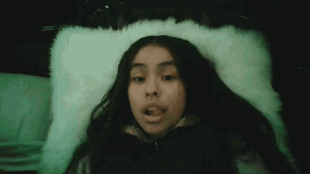 a girl laying on a bed with a white pillow