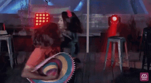 a man in a red shirt is dancing with a woman in a black top in a dark room .