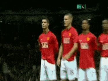 a group of soccer players standing in front of a tv screen
