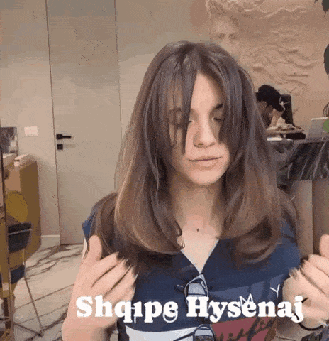 a woman with long hair is wearing a blue shirt that says tommy hilfiger on it
