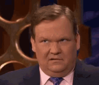 a man in a suit and tie is making a face .