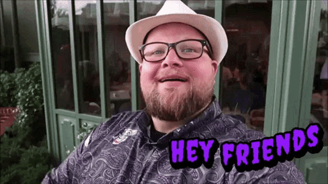 a man wearing glasses and a hat is smiling with the words hey friends above him