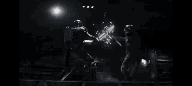 two men are fighting with swords in the dark in a room .