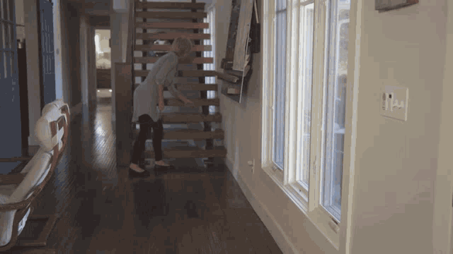 a woman is walking down a set of wooden stairs
