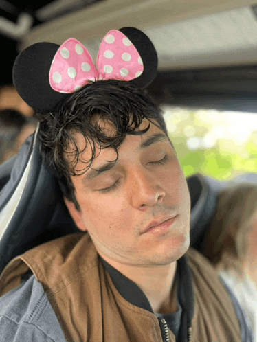 a man wearing minnie mouse ears is sleeping